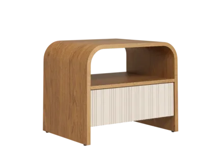 Modern curved wooden bedside table with fluted drawer and open shelf beside an upholstered bed.